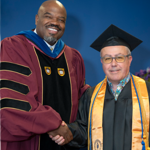 Massachusetts State Education Secretary Patrick Tutweiler shakes the hand of graduate Arthur Nigro