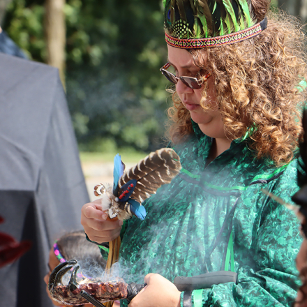 Person waving smoke with a hawk feather during an indigenous land acknowledgement ceremony